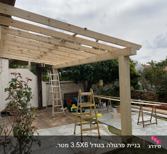 בנייה של פרגולה מעץ עם סולמות וכלי עבודה